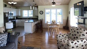 Une cuisine spacieuse avec un plafond en bois, un coin repas avec une table et des chaises, et un salon avec un canapé.