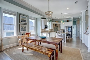 Cozy living area with a large dining table, chandelier, and window overlooking the space.