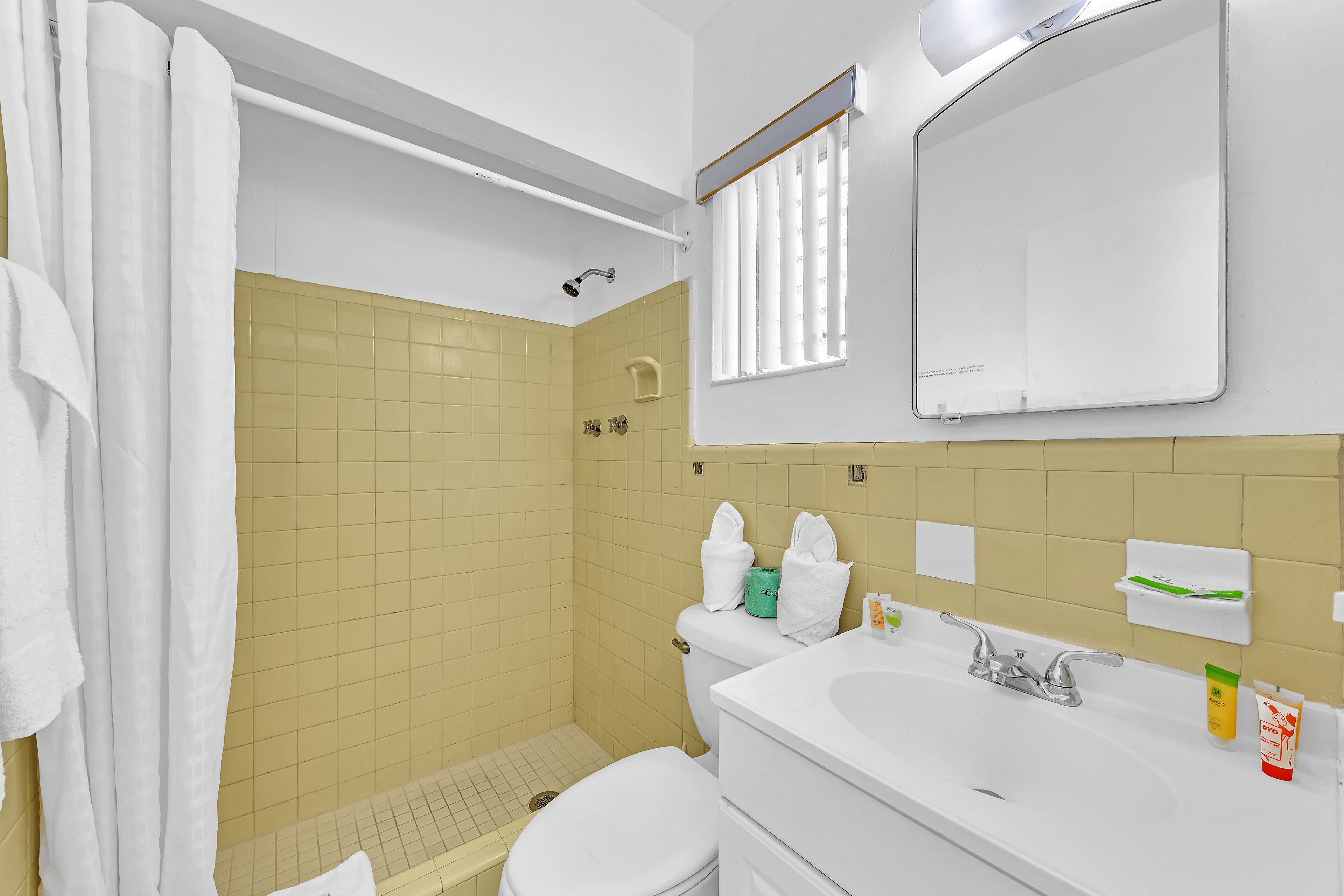 Een badkamer met douche, toilet, wastafel en spiegel.