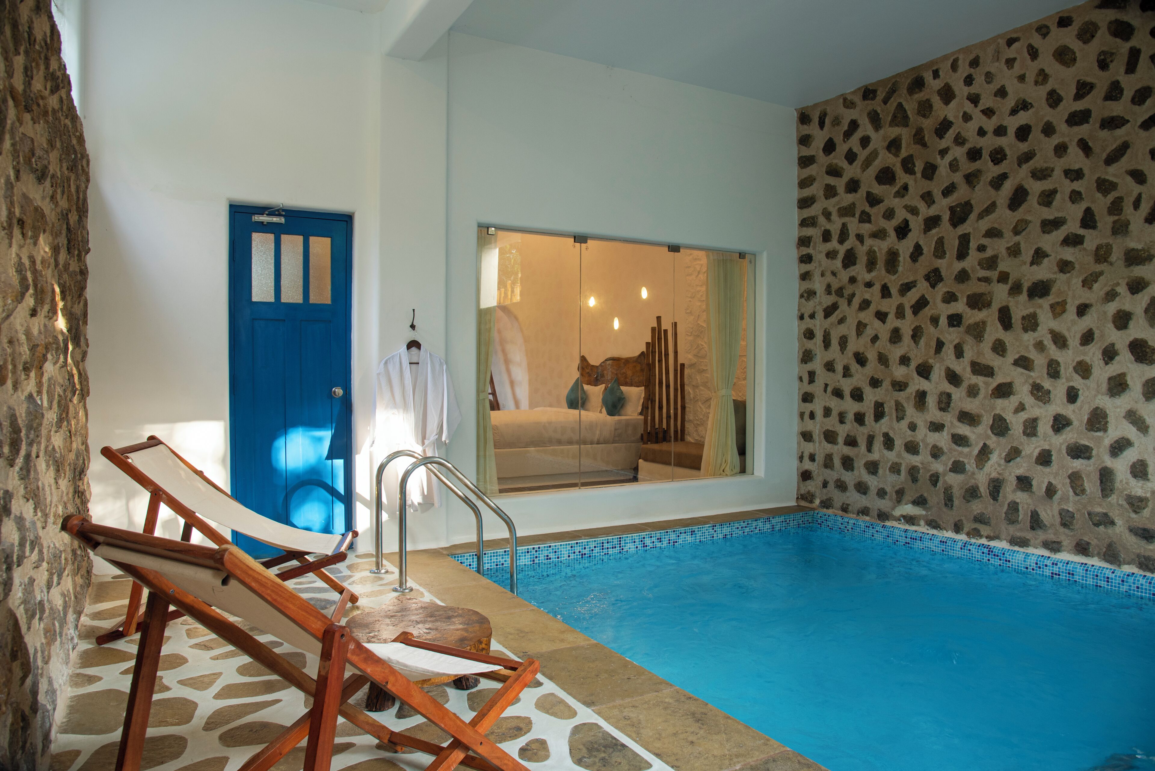 A swimming pool with a stone wall and a blue door.