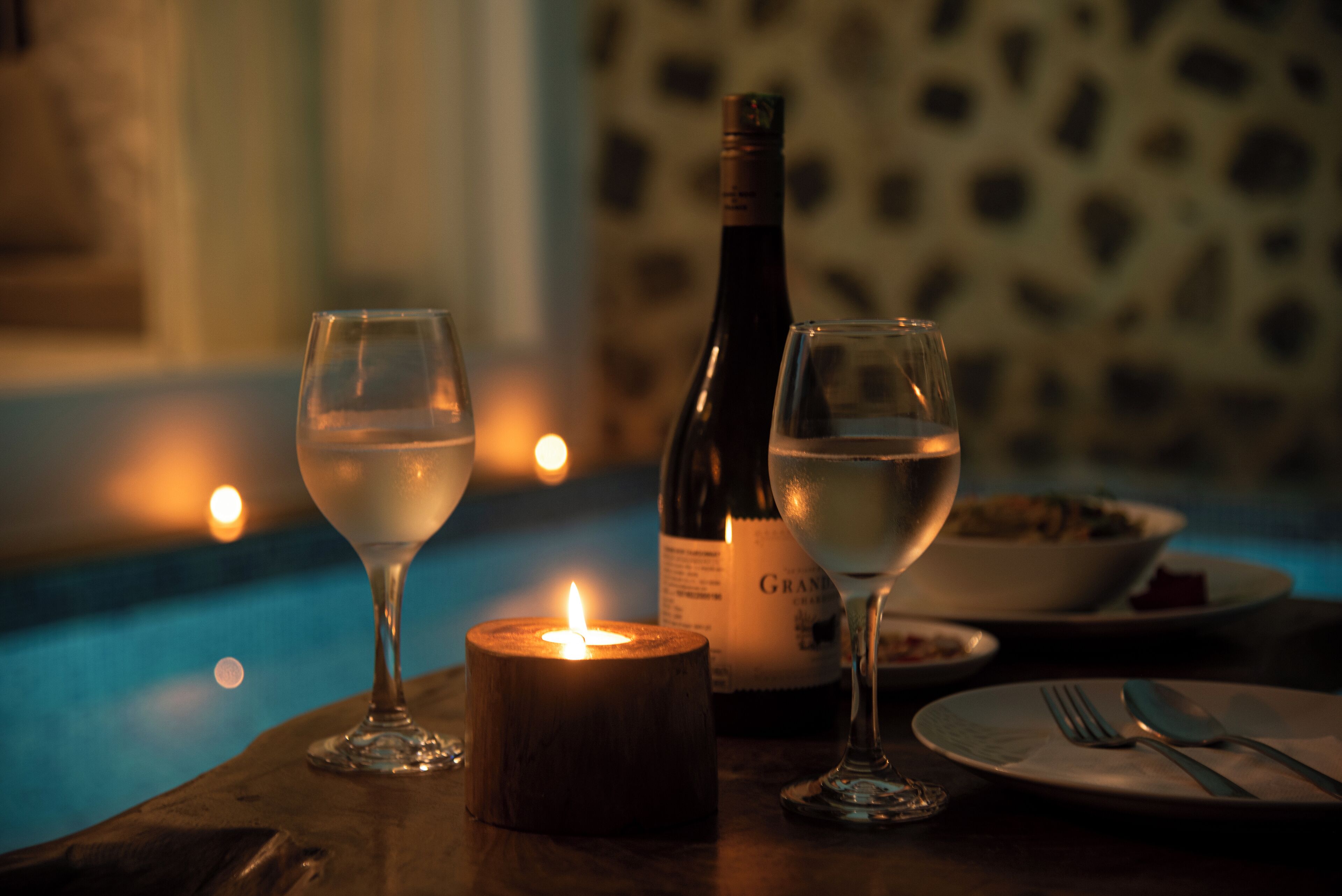 A table with two wine glasses, a candle, and a bottle of wine.