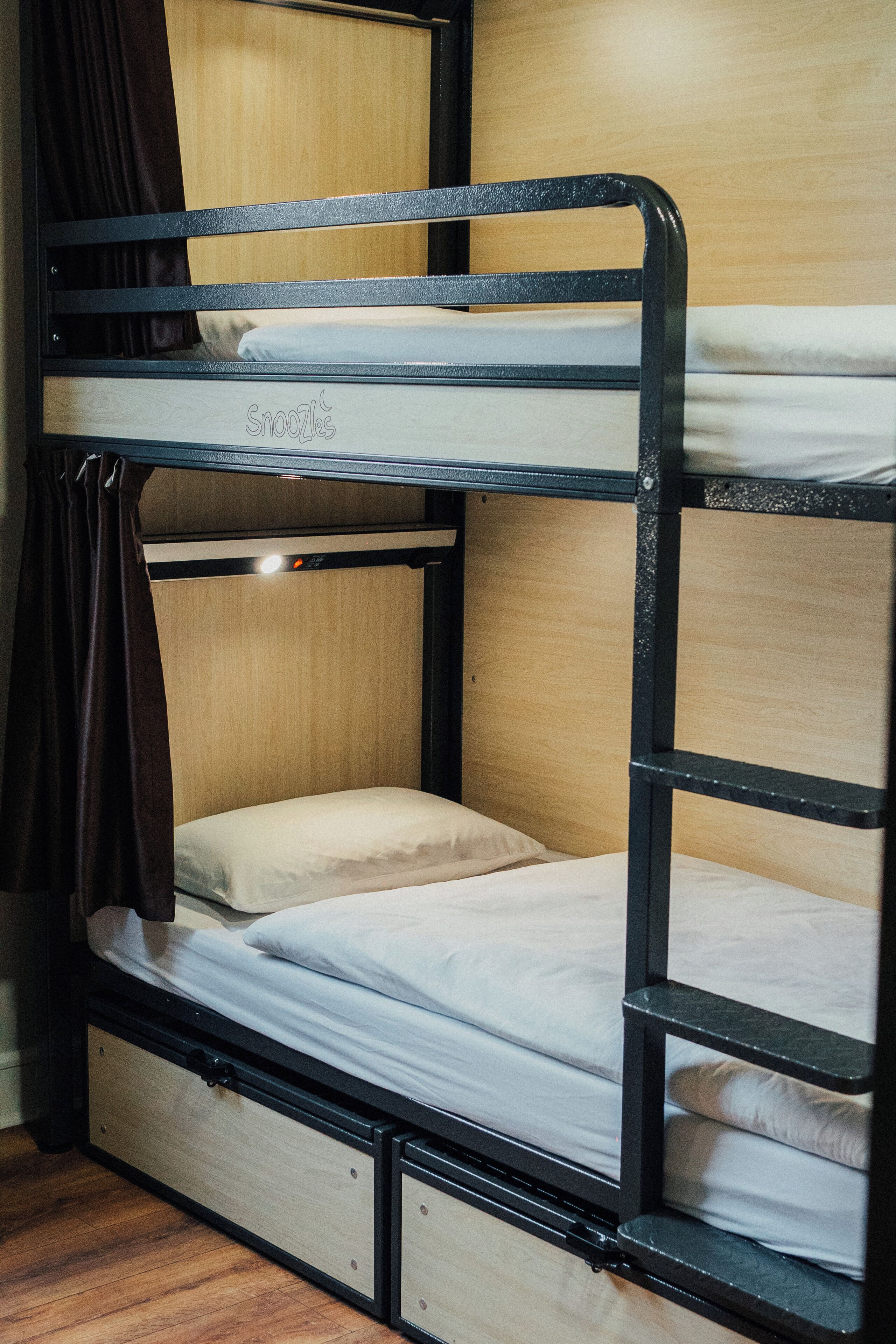 A bunk bed with a wooden headboard and a lower bunk with a storage drawer.