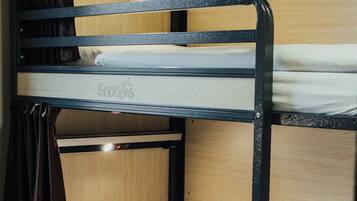 A bunk bed with a wooden headboard and a lower bunk with a storage drawer.