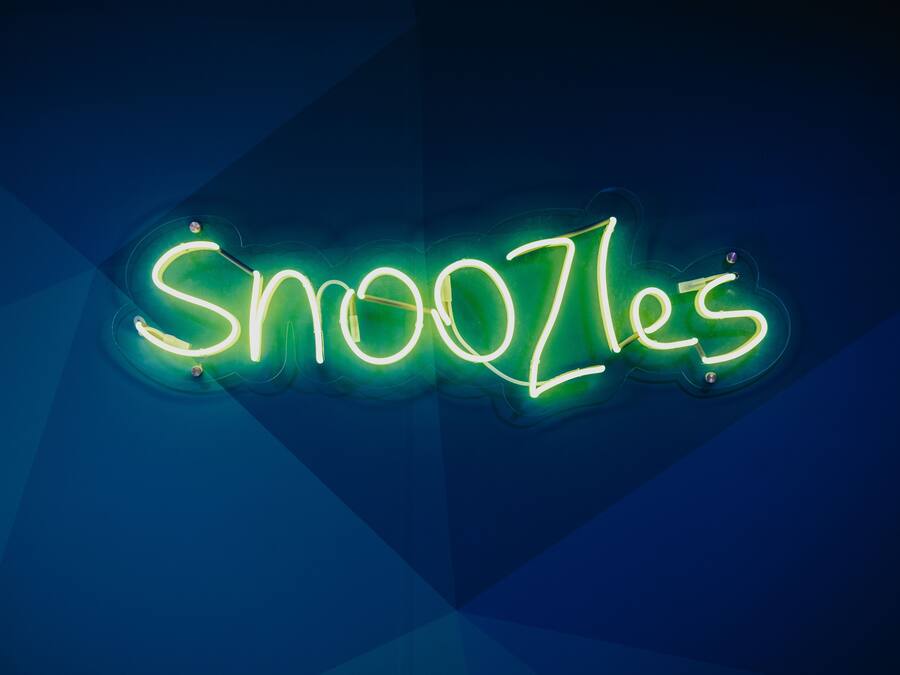 Un letrero de neón con la palabra 'Snoozles' en una tipografía estilizada.