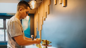 Une personne est en train d’éplucher des bananes à une table, devant une présentation de fruits.