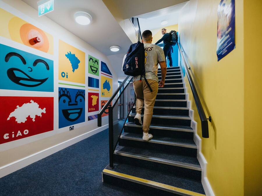 A staircase with colorful wall art, a handrail, and a person descending.