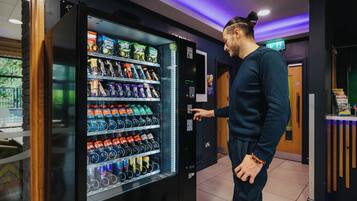 A man interacting with a vending machine stocked with various beverages and snacks.