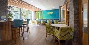 Een restaurant met houten vloeren, groene en gele gestreepte stoelen, en een neonbord waarop 