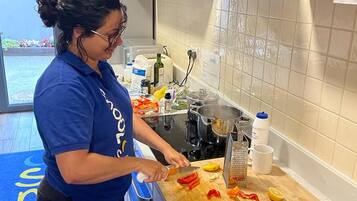 Una persona preparando comida en una cocina con armarios de madera, un respuesto de azulejos y un tapete azul en el suelo.