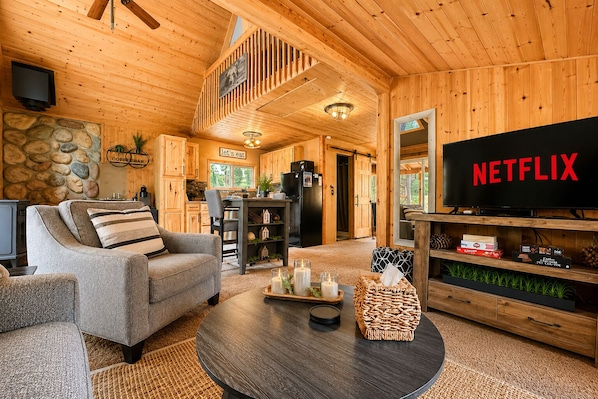 A cozy cabin interior with a living room, kitchen, and dining area.