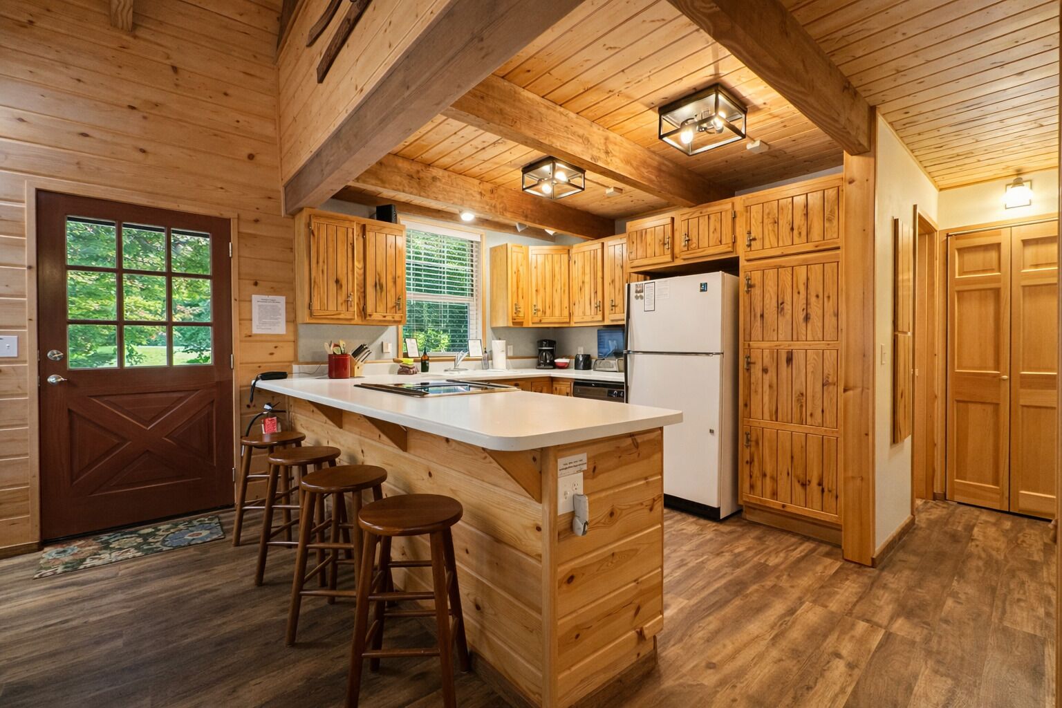 A wooden cabin kitchen with a central island, bar stools, and built-in cabinets.