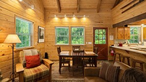 A cozy cabin interior with wooden walls, a dining area, and a kitchen.