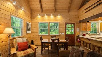 A cozy cabin interior with wooden walls, a dining area, and a kitchen.