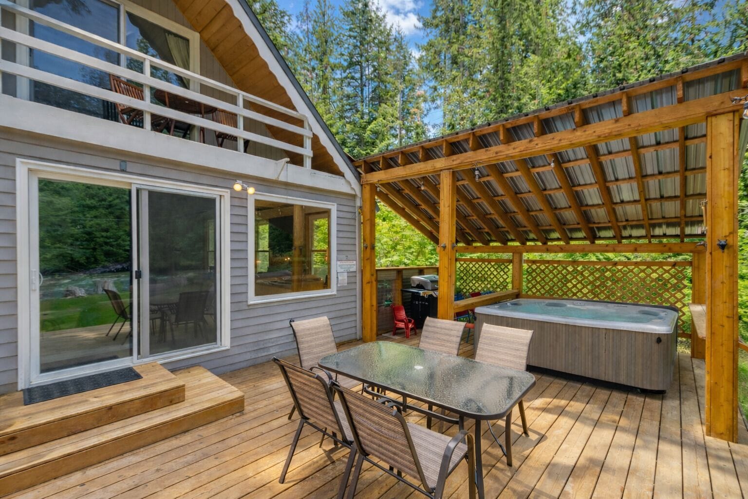A deck with a hot tub, outdoor seating, and a covered area with a pergola.