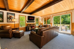 Un salón acogedor con un sofá de cuero, un televisor y un ventanal con vistas a una terraza.