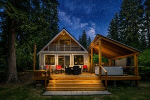 Eine Hütte mit Terrasse, Sitzgelegenheiten im Freien und einem Whirlpool.