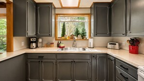 A kitchen with dark cabinets, a window with a view of trees, a coffee maker, and a toaster. - Chiwawa River Chalet 3 Bedroom Home by NW Comfy Cabins by RedAwning (Leavenworth)