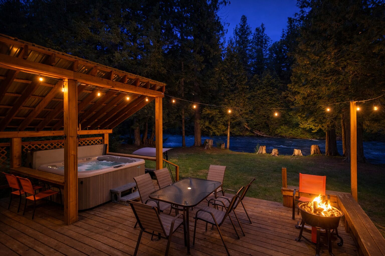 Una terraza de madera con jacuzzi, mobiliario exterior e iluminación con luces colgantes.