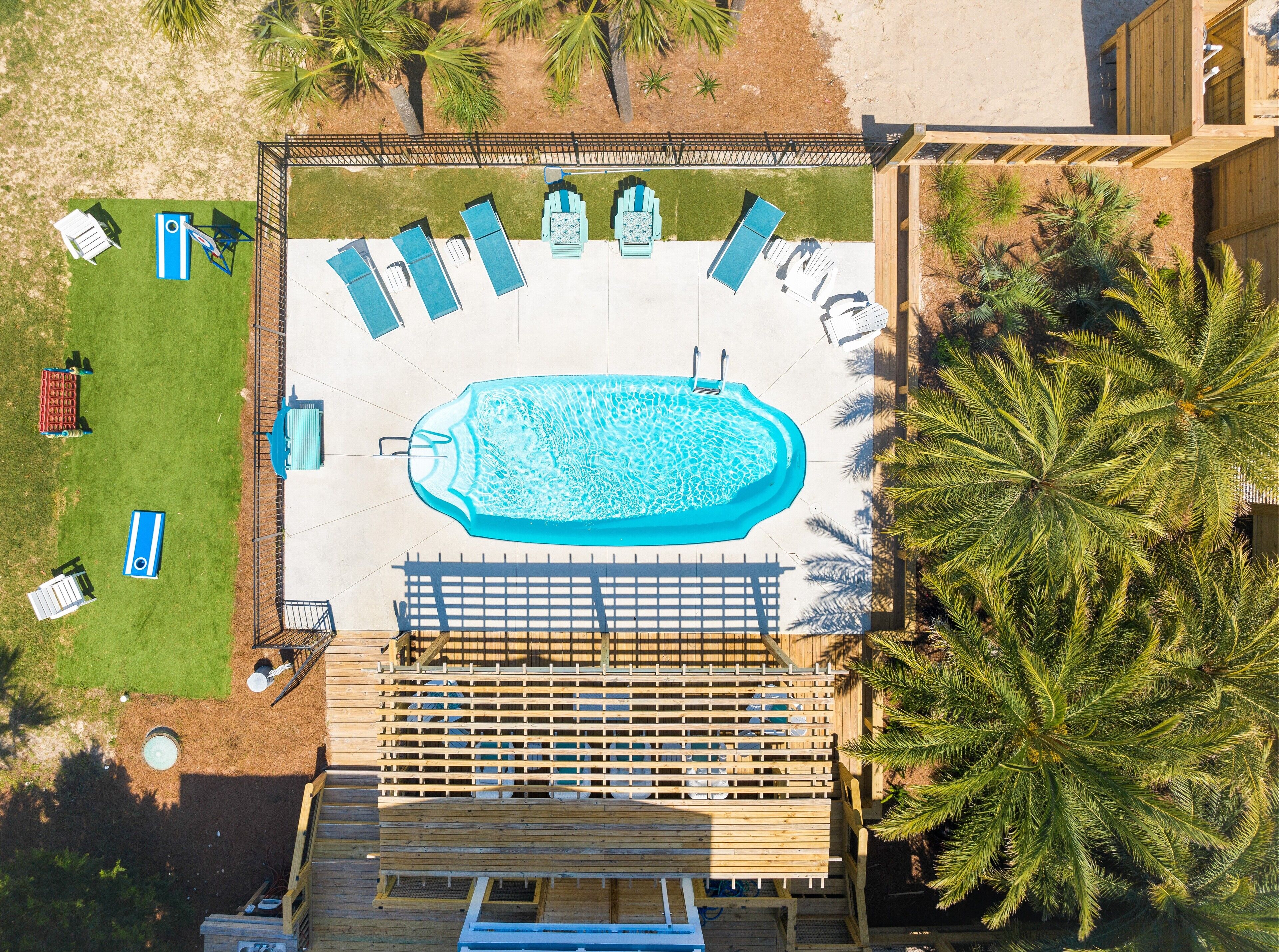 An aerial view of a swimming pool area with multiple lounge chairs and a wooden deck.