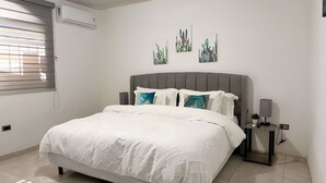 Ein Schlafzimmer mit einem großen Bett, einem Nachttisch mit Lampe und einem Kunstwerk an der Wand.