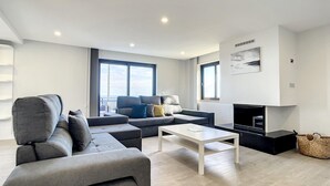 Ein modernes Wohnzimmer mit einem grauen Sofa, einem weißen Couchtisch und einem flachbildfernseher an der Wand.