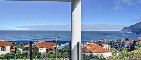 A balcony with a view of the ocean and coastal town.