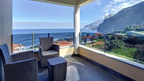 Ein Balkon mit Korbmöbeln und Blick auf das Meer und die Küstenarchitektur.