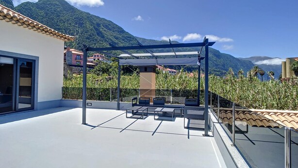 Terraza en la azotea con pérgola y zona de estar, con vistas a un paisaje montañoso.