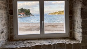 A room with a stone wall and a window overlooking a beach and sea. - Villa Diocletian***** Solta, Premium traditional stone house next to the sea (Rogac)
