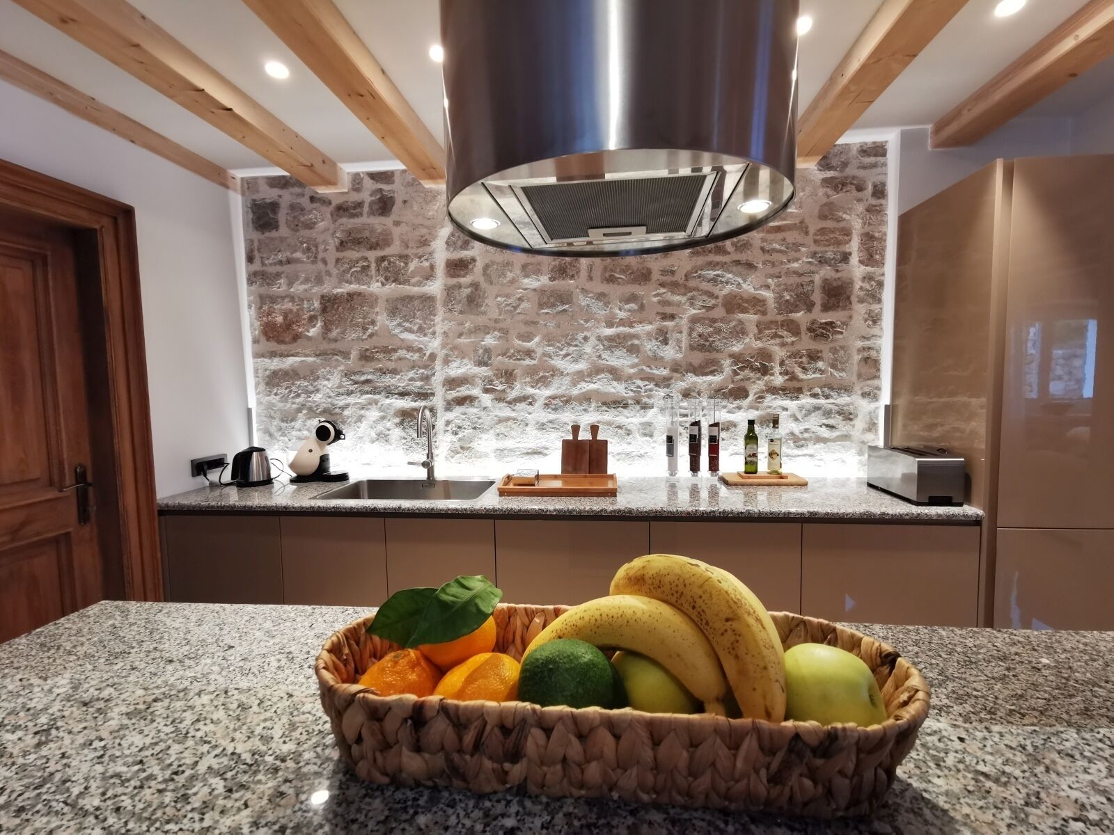 Eine Küche mit Steinrückwand, Granit Arbeitsplatte und einer Obstschale.