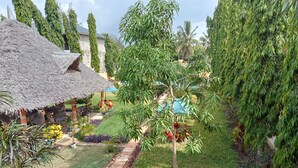 A thatched-roof outdoor seating area with a pathway leading to a building. - MODERN SOUTH HOTEL (Diani Beach)