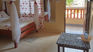 A room with a bed, a table, and a balcony. - MODERN SOUTH HOTEL (Diani Beach)