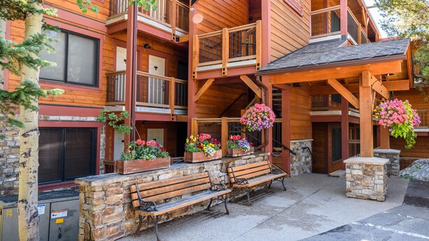 Un chalet en bois doté de plusieurs balcons, d’un escalier en pierre et d’un espace salon extérieur.