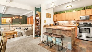Une cuisine moderne dotée d’un îlot central, d’un four encastré et de meubles de rangement en bois.