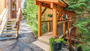 Une terrasse en bois avec une rambarde en bois, un chemin en pierre et un escalier en bois menant à un bâtiment.