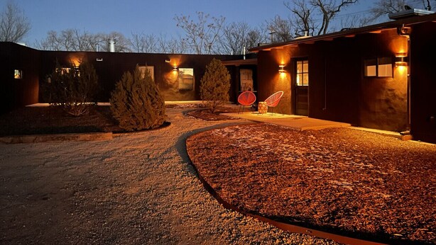 A building with a gravel driveway and a curved path leading to a seating area with two chairs. - Luxurious 1bd Charmer  `Poni Suite` @ La Dea (Santa Fe)