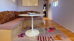 A cozy living area with a wooden ceiling, a round white table, a patterned rug, and a bench with cushions. - Luxurious 1bd Charmer  `Poni Suite` @ La Dea (Santa Fe)