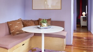 A cozy room with a wooden ceiling, a round table with a white base, a patterned sofa, and a colorful rug. - Luxurious 1bd Charmer  `Poni Suite` @ La Dea (Santa Fe)