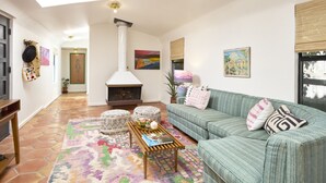 A cozy living room with a fireplace, a sofa, ottomans, and a coffee table. - Bright, Playful 2bd `Atami Suite` @ La Dea (Santa Fe)