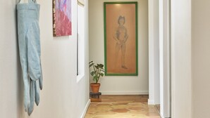 A hallway with a tiled floor, a wall-mounted hat rack, a framed artwork, and a potted plant. - Bright, Playful 2bd `Atami Suite` @ La Dea (Santa Fe)