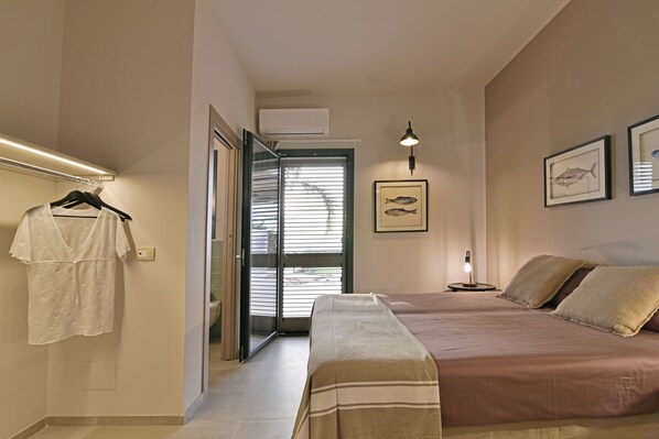 A bedroom with a bed, a nightstand, a wall-mounted lamp, and a framed fish picture. - Rariki, hillside villa, 4 minutes from beaches and views of the Ragusa coast. (SCICLI)