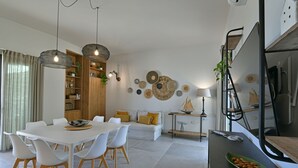 Un espace de vie moderne comprenant un coin repas, un canapé et un comptoir de cuisine.