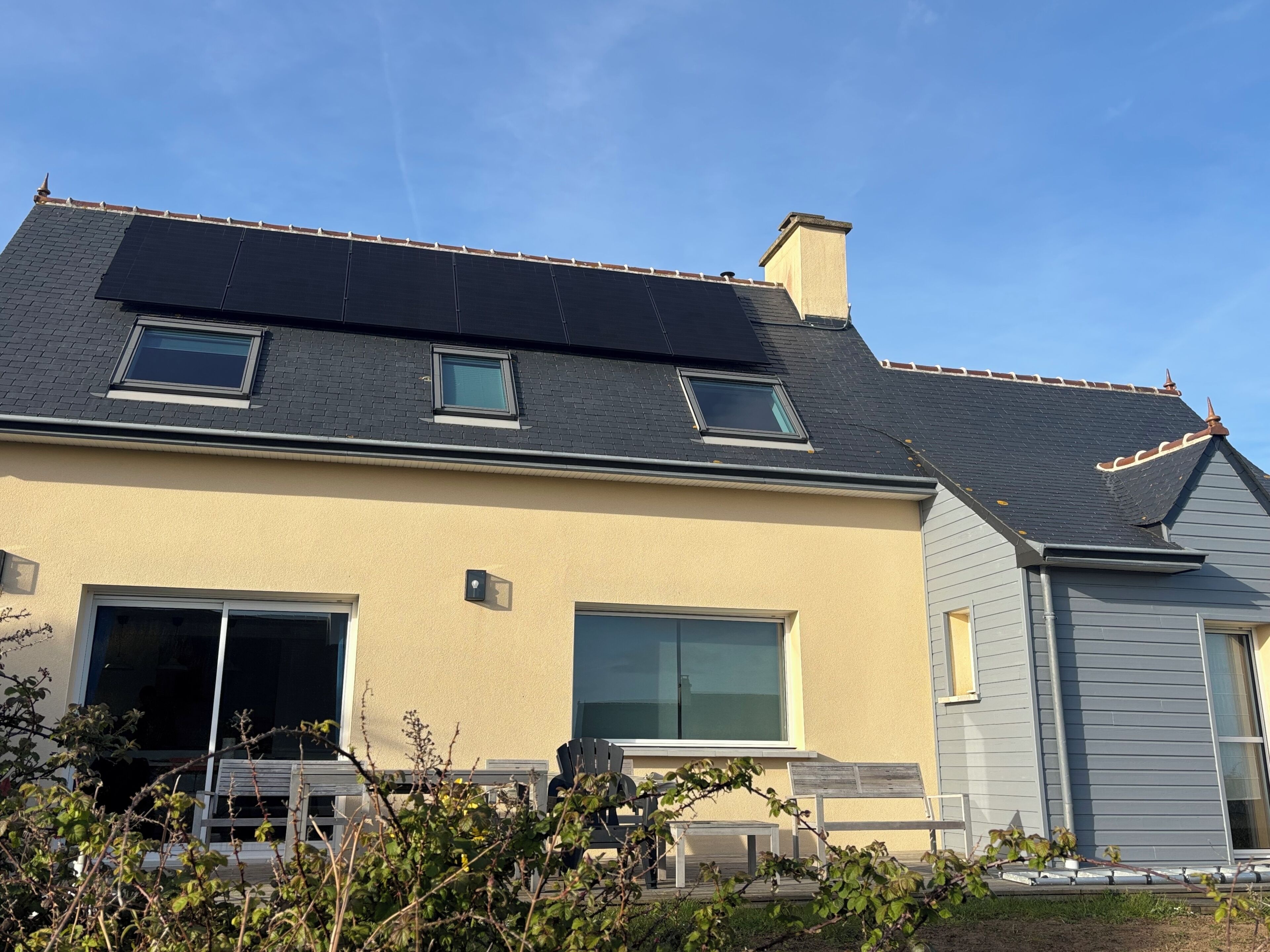 Una casa con techo inclinado, paneles solares y garaje.