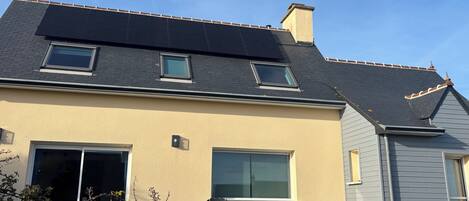 Una casa con techo inclinado, paneles solares y garaje.