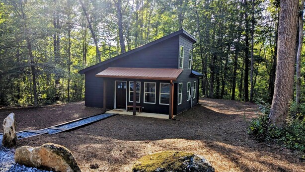 A modern two-story house with a dark exterior, large windows, and a covered porch. - Romantic Retreat | Dual-Head Shower for Two (Sautee)
