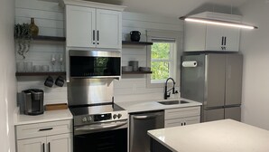 A modern kitchen with white cabinetry, stainless steel appliances, a built-in oven, microwave, and refrigerator. - Romantic Retreat | Dual-Head Shower for Two (Sautee)