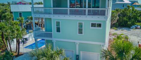 A multi-story house with a pool, a golf cart, and palm trees.