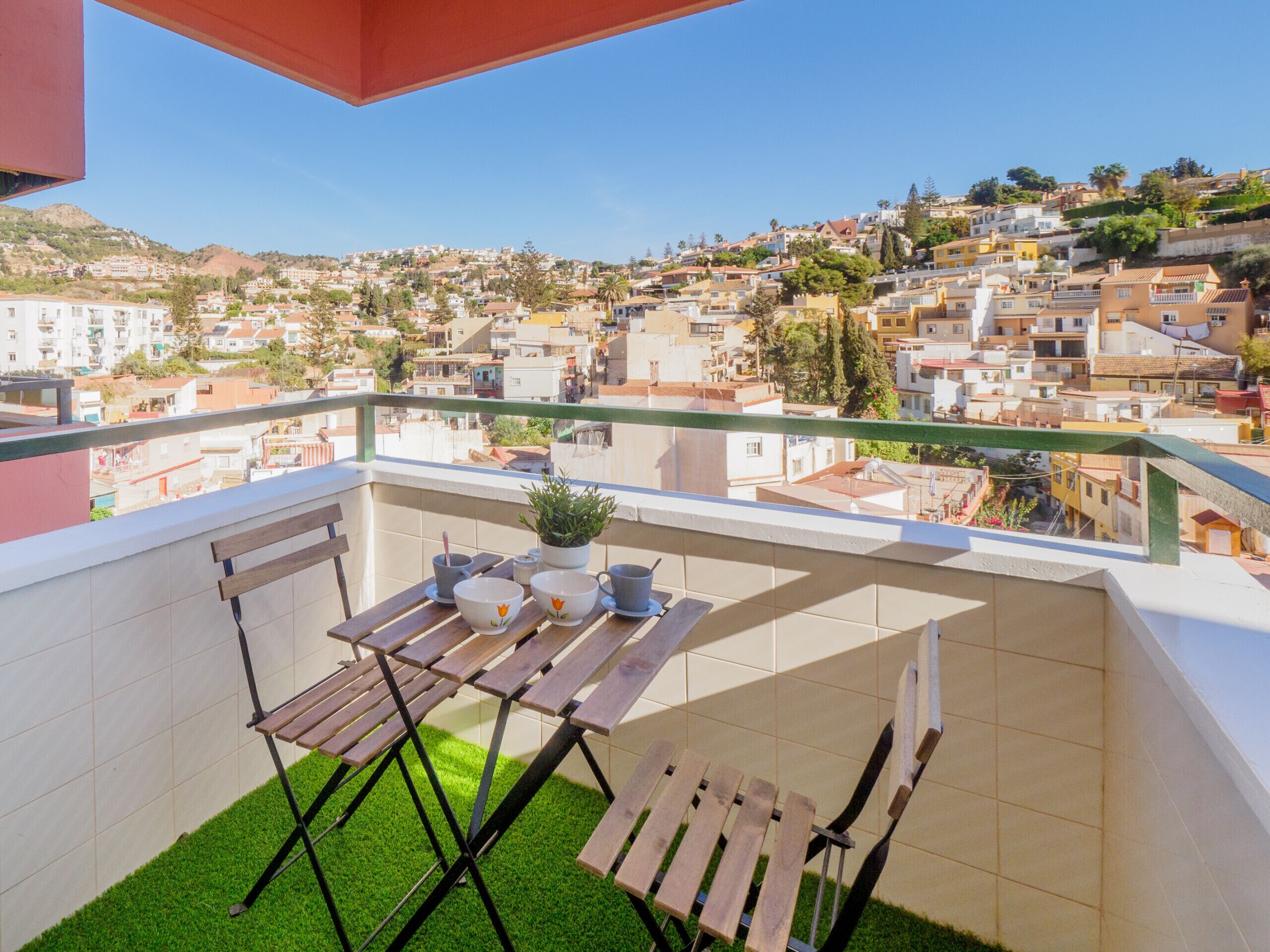 Un balcone con vista su una cittadina collinare densamente popolata.