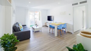 Un salon moderne avec un canapé, une table à manger et des chaises, un téléviseur et un balcon avec vue.