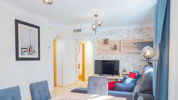 Een moderne woonkamer met een eettafel, banken en een televisie.